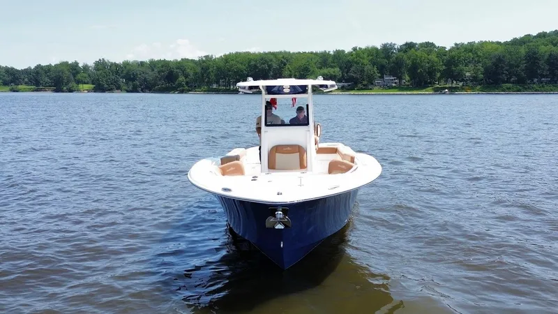 Slide: The Image of 2023 NauticStar 28 XS boat on a calm lake with lush green shoreline. - 6
