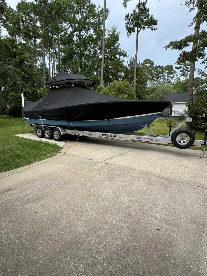 Slide: The Image of 2023 Regulator 30XO boat covered on a trailer in a driveway. - 13