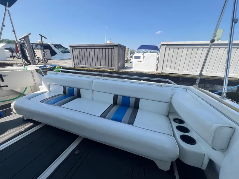 Slide: The Image of 1991 Sea Ray 310 Sundancer boat interior with white and blue seating at a marina. - 10