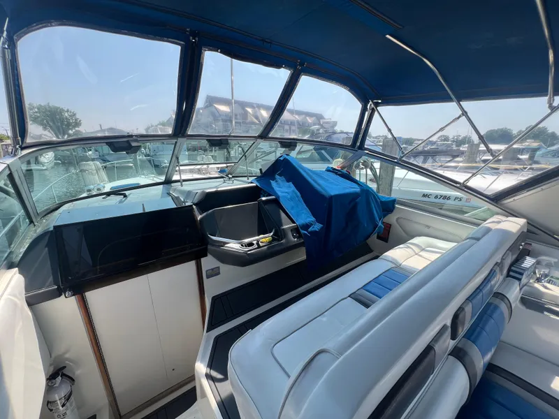 Slide: The Image of 1991 Sea Ray 310 Sundancer interior with blue canopy and seating at marina. - 12