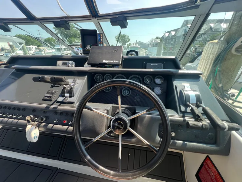 Slide: The Image of 1991 Sea Ray 310 Sundancer helm with steering wheel, gauges, and Raymarine navigation system. - 14