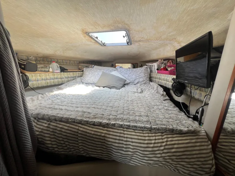 Slide: The Image of Cozy cabin interior of 1991 Sea Ray 310 Sundancer with bed, skylight, and TV. - 22
