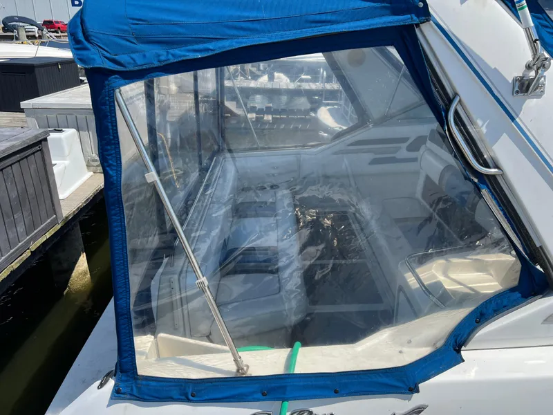 Slide: The Image of 1991 Sea Ray 310 Sundancer boat with blue canopy and clear enclosure at dock. - 5