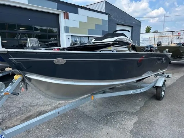 Slide: The Image of 2026 Lund 1600 Fury Tiller boat on trailer, parked outside a building. - 1