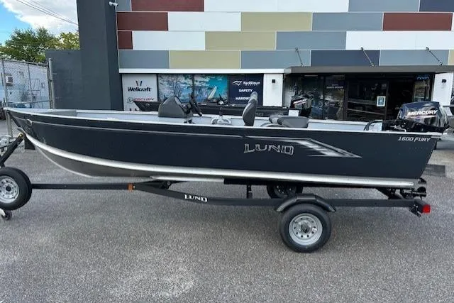 The Image of 2026 Lund 1600 Fury SS fishing boat on trailer, parked outside a dealership. - 0
