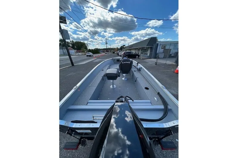 Slide: The Image of 2026 Lund 1600 Fury SS boat on a trailer, parked on a street under a blue sky. - 5