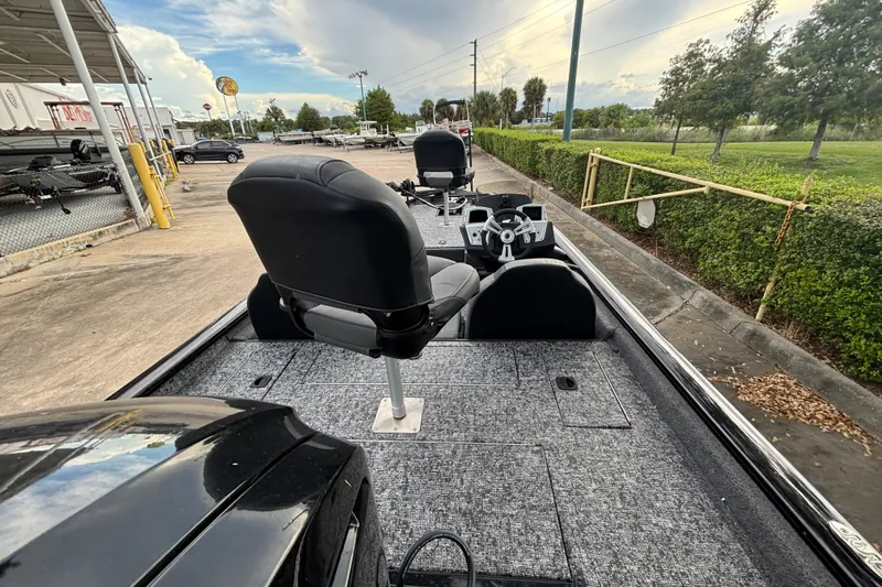 Slide: The Image of 2025 Tracker Pro Team 175 boat with seating and steering, parked outdoors. - 2