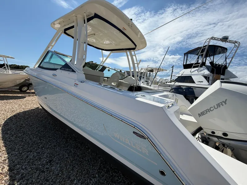 Slide: The Image of 2021 Boston Whaler 240 Vantage boat with Mercury engine, docked under a clear sky. - 3