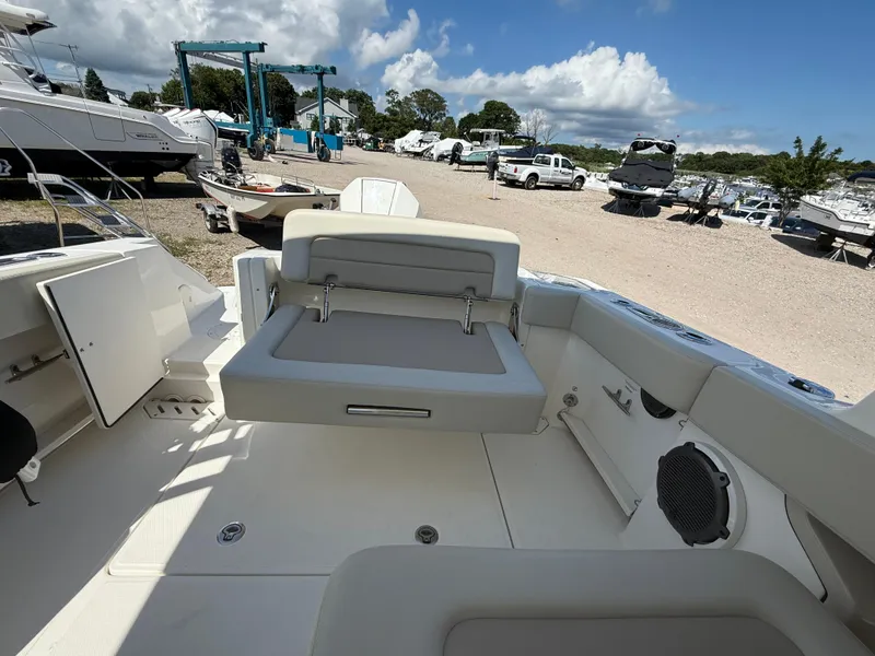 Slide: The Image of 2021 Boston Whaler 240 Vantage boat interior with seating, docked outdoors under a blue sky. - 5