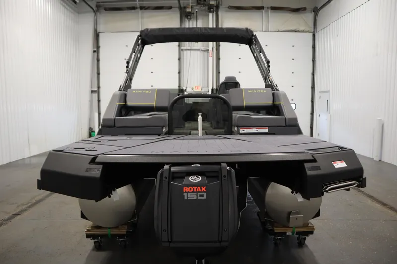 Slide: The Image of 2025 Manitou 24 Explore Switchback Tritoon in a garage, featuring Rotax 150 engine. - 6