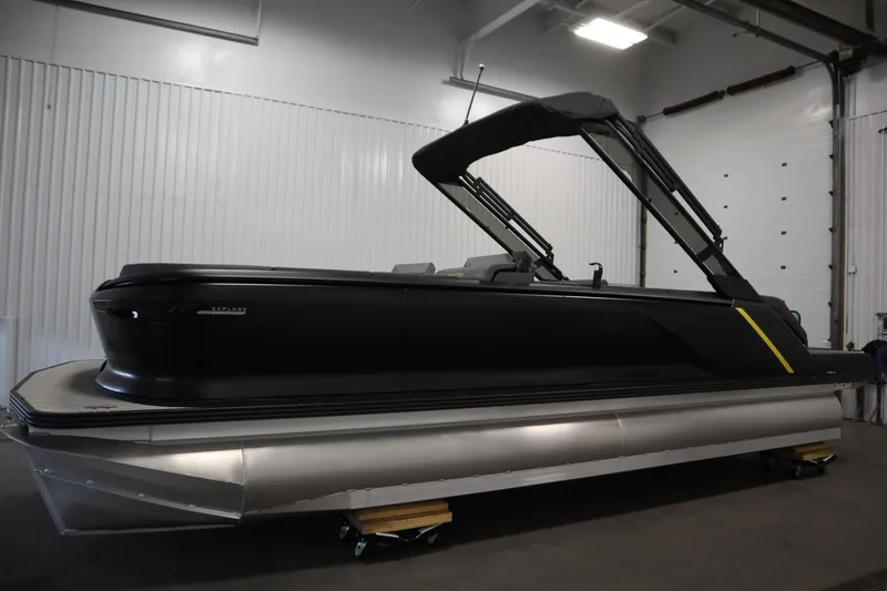 Slide: The Image of 2025 Manitou 24 Explore Switchback Trifold Tritoon in a showroom, side view. - 8