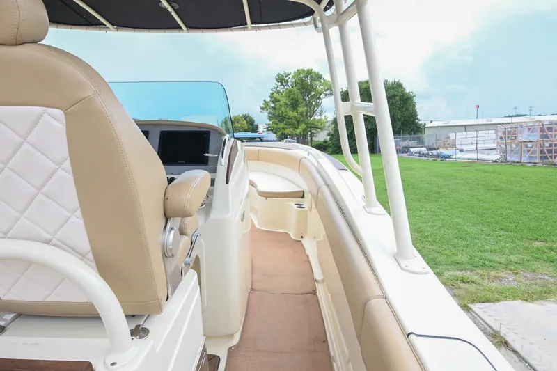 Slide: The Image of 2016 Chris-Craft Catalina 29 boat interior with tan seating and helm, parked on grass. - 25