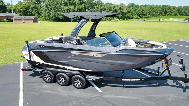 Slide: The Image of 2025 Tigé Ultré 23ZX boat on trailer, parked on asphalt near grassy area. - 6