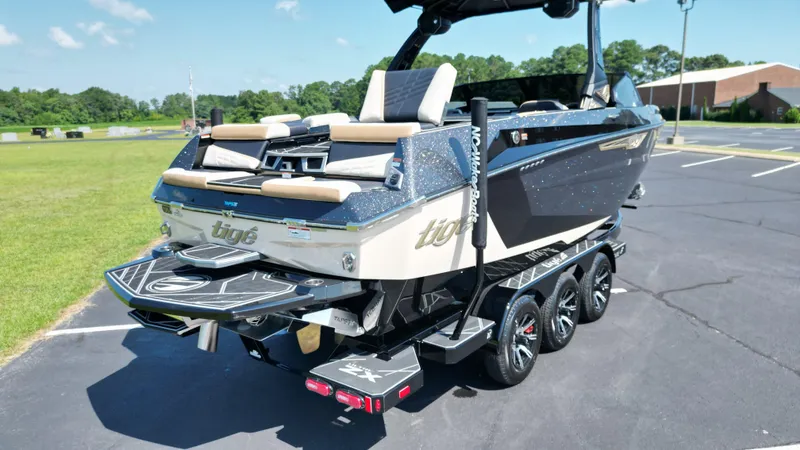 Slide: The Image of 2025 Tigé Ultré 23ZX boat on trailer, parked outdoors, showcasing sleek design and modern features. - 8