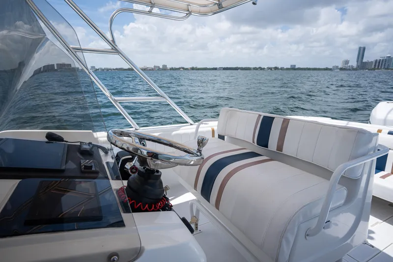 Slide: The Image of 1999 Intrepid 35 boat interior with striped seating and steering wheel, overlooking ocean and cityscape. - 13