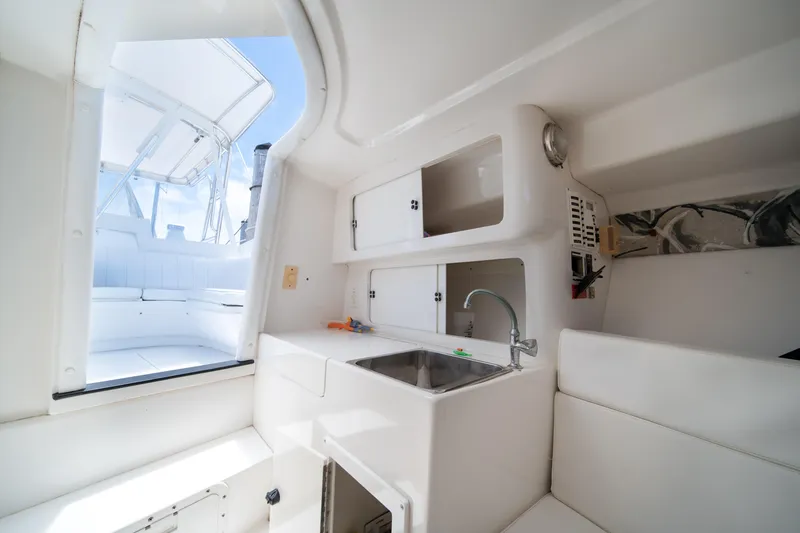 Slide: The Image of Interior of a 1999 Intrepid 35 boat featuring a compact kitchenette and seating area. - 25