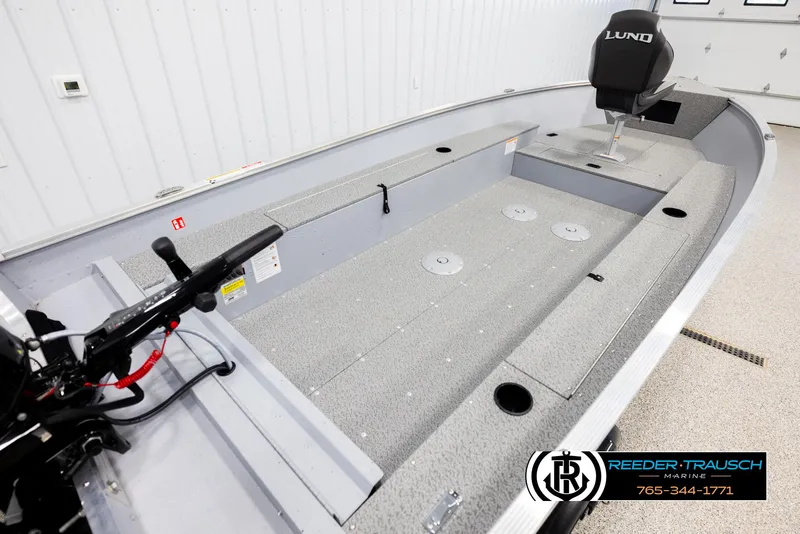 Slide: The Image of 2026 Lund 1600 Fury Tiller boat interior with seating and controls, showcased in a showroom. - 10