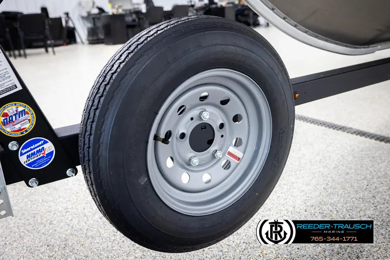 Slide: The Image of 2026 Lund 1600 Fury Tiller trailer wheel with certification stickers, displayed indoors. - 32