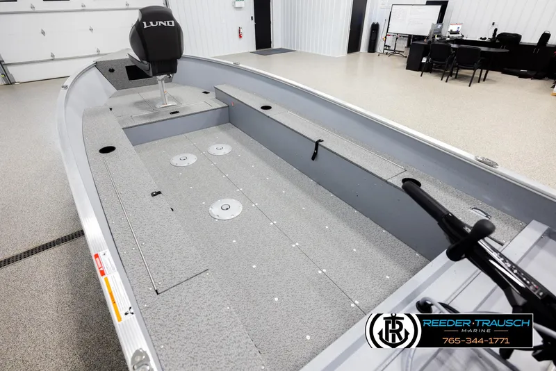 Slide: The Image of 2026 Lund 1600 Fury Tiller boat interior in showroom, featuring spacious seating and controls. - 9