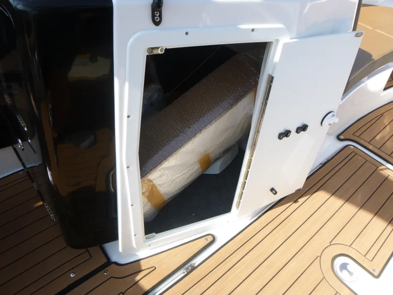 Slide: The Image of 2025 Yamaha Boats 222SD storage compartment with open door on teak deck. - 12