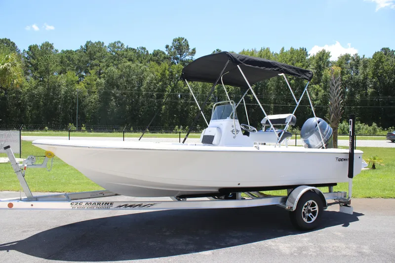 Slide: The Image of 2026 Tidewater 1910 Bay Max boat on trailer, parked outdoors with trees in background. - 25