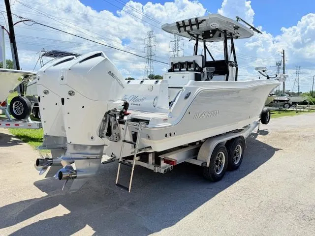 Slide: The Image of 2022 Blackfin 252 CC boat with dual outboard engines, parked outdoors under a blue sky. - 2