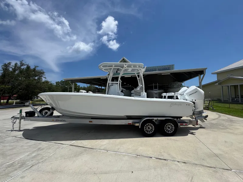 The Image of 2026 Yellowfin 26 Hybrid boat on trailer under clear blue sky. - 0