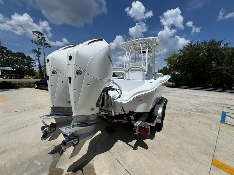 Slide: The Image of 2026 Yellowfin 26 Hybrid boat with dual outboard motors on a trailer, under a partly cloudy sky. - 12