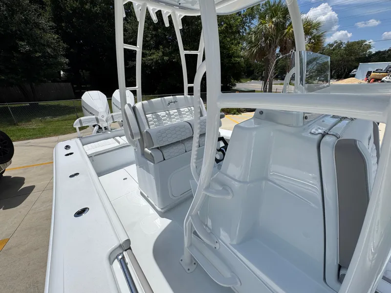 Slide: The Image of 2026 Yellowfin 26 Hybrid boat interior with seating and console, parked outdoors. - 26