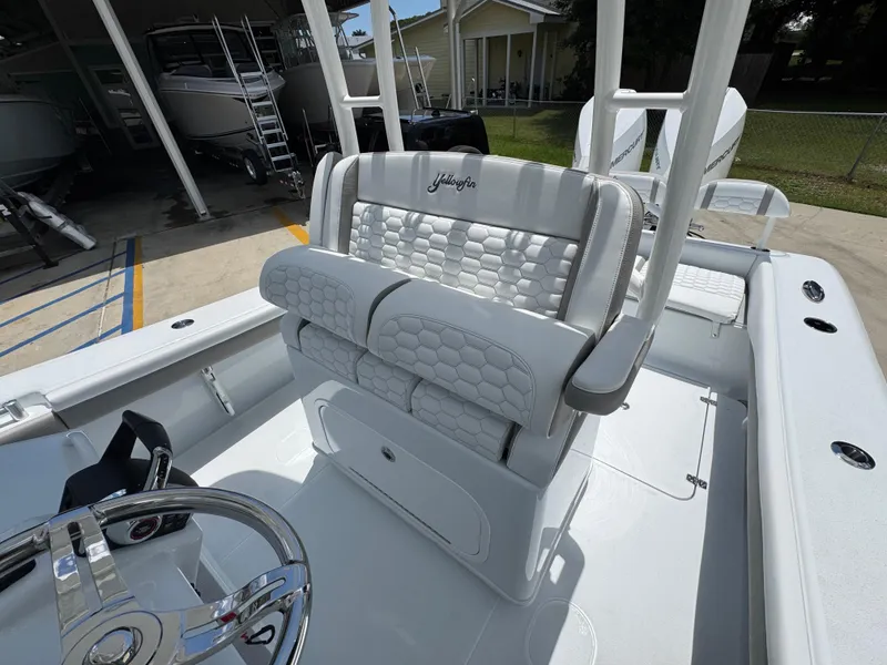 Slide: The Image of 2026 Yellowfin 26 Hybrid boat interior with white cushioned seating and steering wheel. - 27