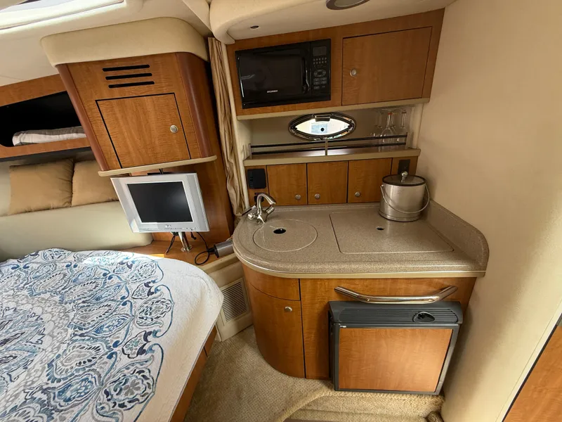 Slide: The Image of 2006 Sea Ray 290 Sundancer cabin with kitchenette, TV, and bed. - 11
