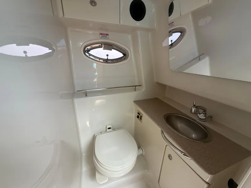 Slide: The Image of 2006 Sea Ray 290 Sundancer bathroom with toilet, sink, and porthole window. - 13