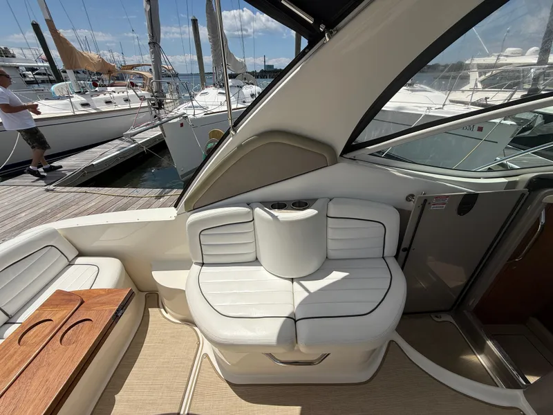 Slide: The Image of 2006 Sea Ray 290 Sundancer interior with white seating and wooden table, docked at marina. - 5