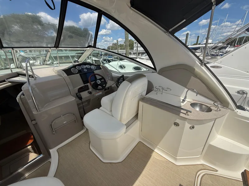Slide: The Image of 2006 Sea Ray 290 Sundancer cockpit with helm, seating, and sink under a clear sky. - 6