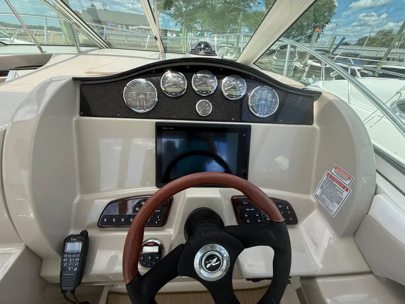 Slide: The Image of 2006 Sea Ray 290 Sundancer helm with gauges, steering wheel, and control panel. - 8