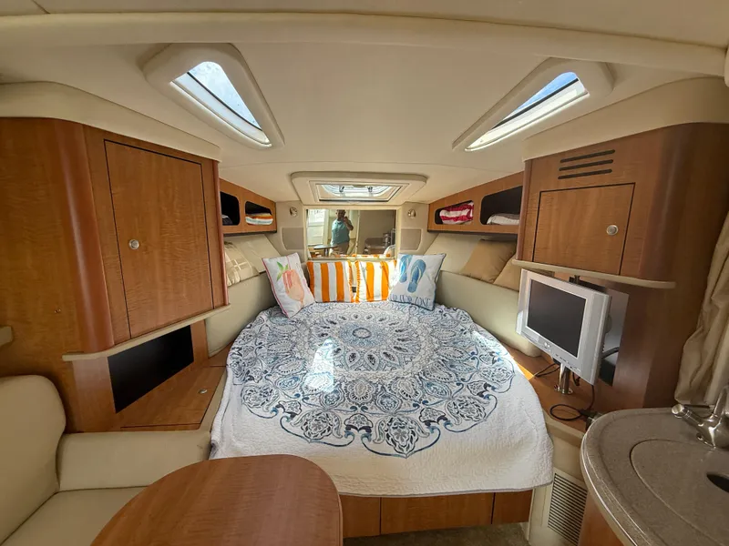 Slide: The Image of Interior of 2006 Sea Ray 290 Sundancer with cozy bed, TV, and wooden cabinetry. - 9