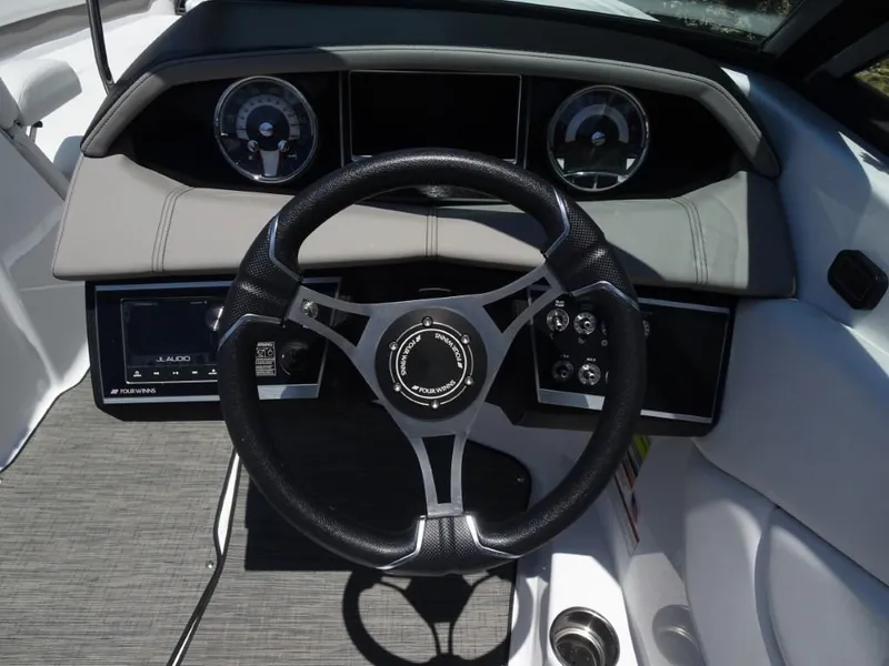 Slide: The Image of 2023 Four Winns H260 boat dashboard with steering wheel and gauges. - 15
