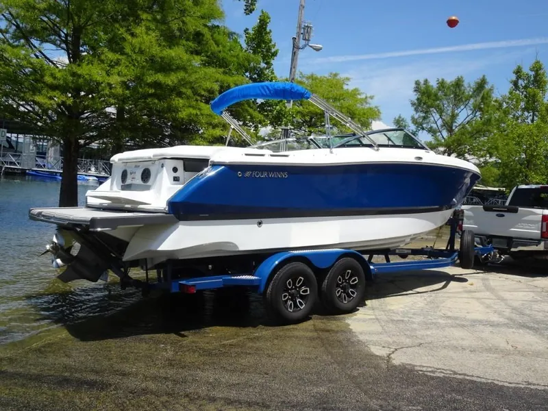 Slide: The Image of 2023 Four Winns H260 boat on trailer near water, surrounded by trees. - 3