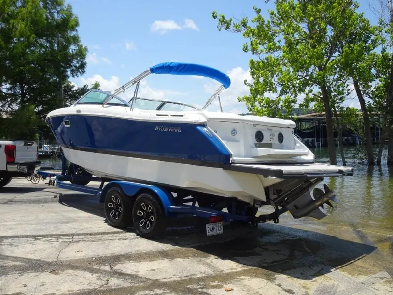 Slide: The Image of 2023 Four Winns H260 boat on trailer by a lake, under clear blue sky. - 6