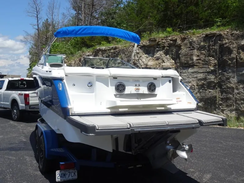 Slide: The Image of 2023 Four Winns H260 boat on trailer, blue canopy, parked near rocky terrain. - 7