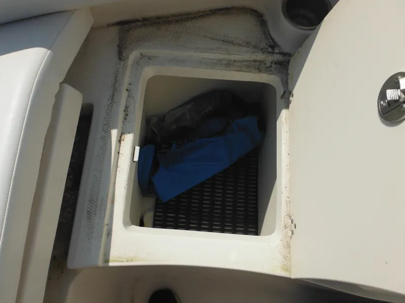 Slide: The Image of Storage compartment on a 2013 Robalo R207 Dual Console boat, partially open with items inside. - 49