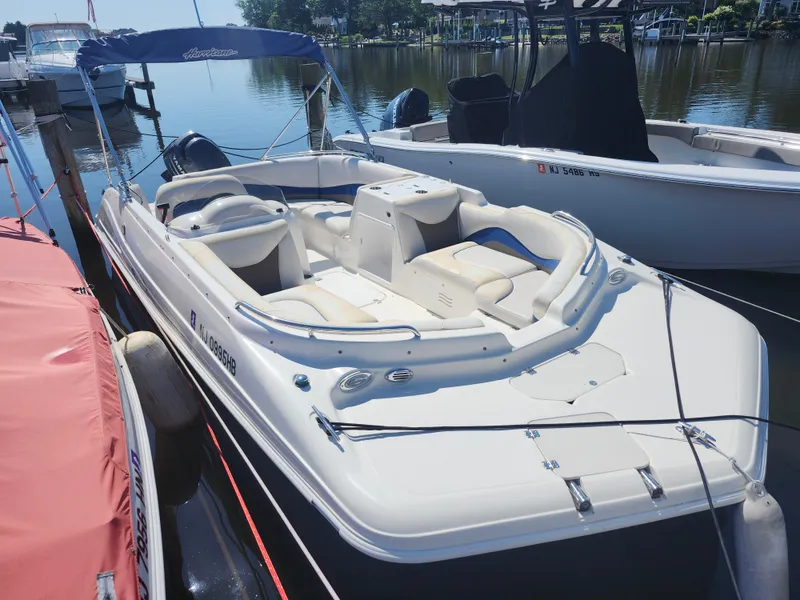 Slide: The Image of 2009 Hurricane SunDeck 2000 OB boat docked at marina, featuring spacious seating and canopy. - 2