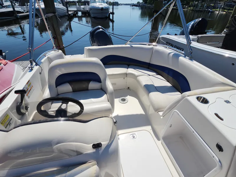 Slide: The Image of 2009 Hurricane SunDeck 2000 OB boat interior with seating and steering wheel, docked at marina. - 4