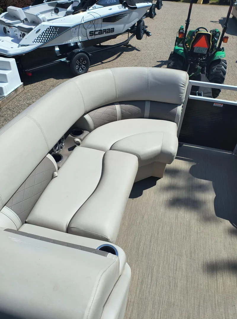 Slide: The Image of Luxurious seating on 2017 Bennington 24 SSBXP-SPS pontoon boat, with nearby watercraft and tractor. - 12