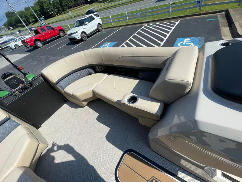 Slide: The Image of 2026 Harris Solstice 230 boat interior with beige seating and cup holders in a parking lot. - 7
