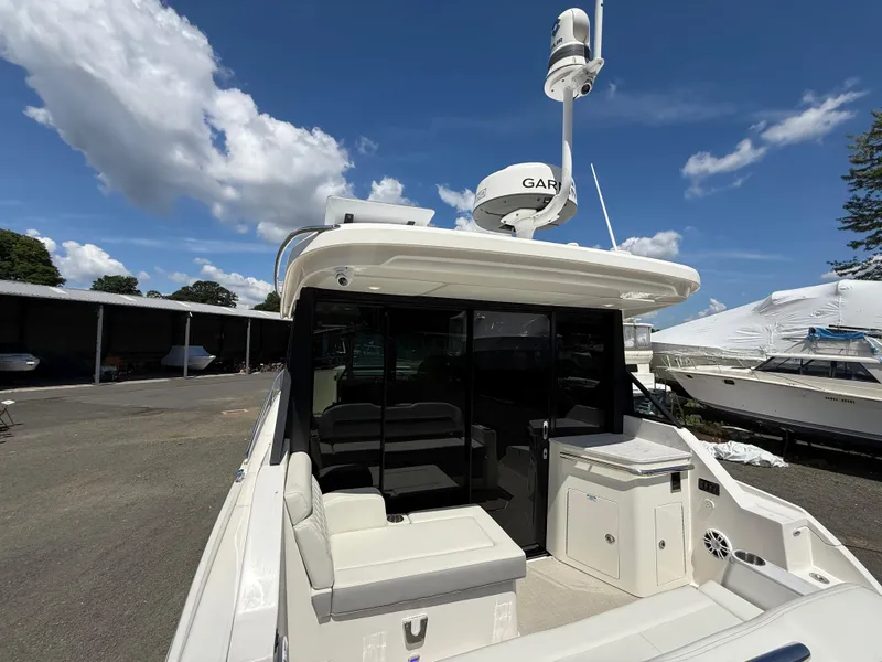 Slide: The Image of 2022 Regal 36 XO yacht with seating area and Garmin radar, docked under a blue sky. - 15