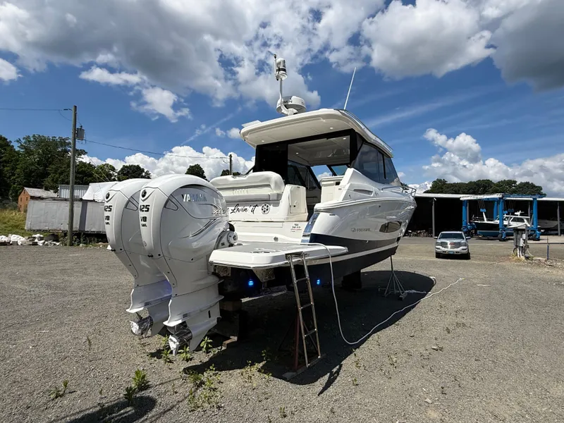 Slide: The Image of 2022 Regal 36 XO boat with twin Yamaha engines, parked outdoors under a cloudy sky. - 2