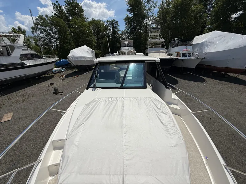 Slide: The Image of 2022 Regal 36 XO boat on land, surrounded by trees and other vessels. - 43