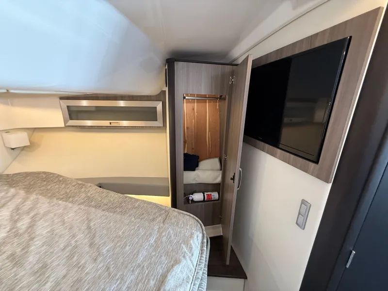Slide: The Image of 2022 Regal 36 XO cabin interior with bed, closet, and mounted TV. - 47