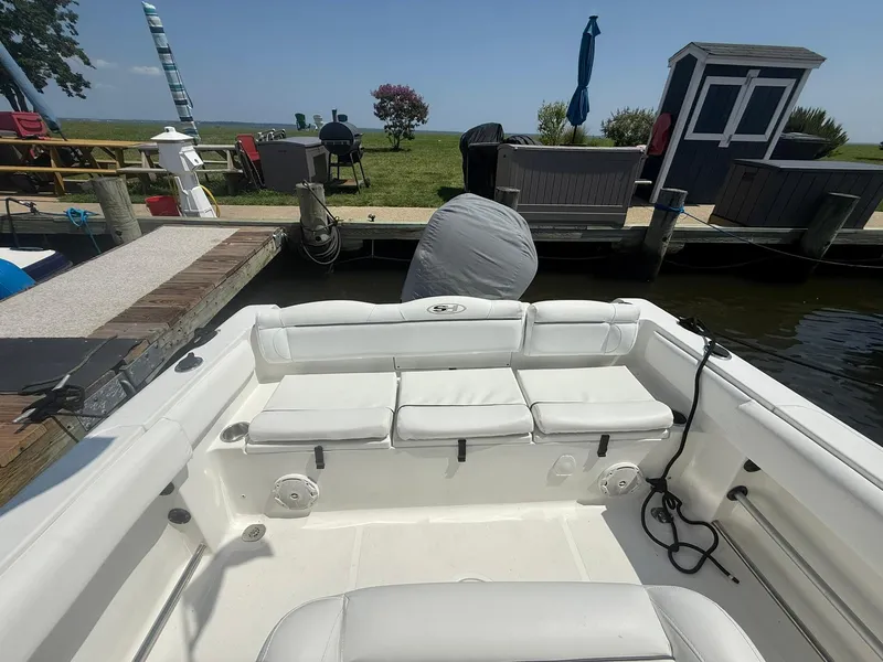 Slide: The Image of 2017 Sea Hunt Ultra 234 boat interior with white seating at dock. - 11